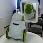 white and green robot with wheels looking in mirror