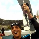 smiling man in wetsuit floating in water beside boat