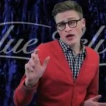 clean cut rosy cheeked young man in glasses and red cardigan