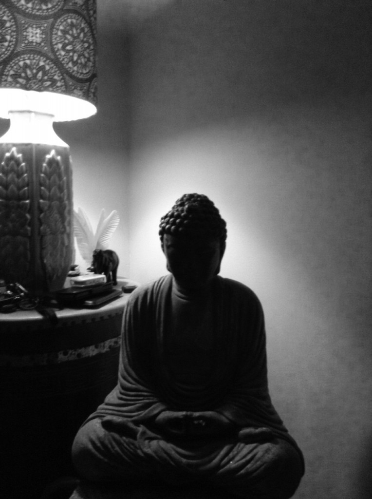 Stone Buddha statue with a lamp in background
