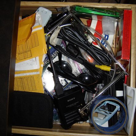 Random junk drawer with various objetcs like sunglasses and cords